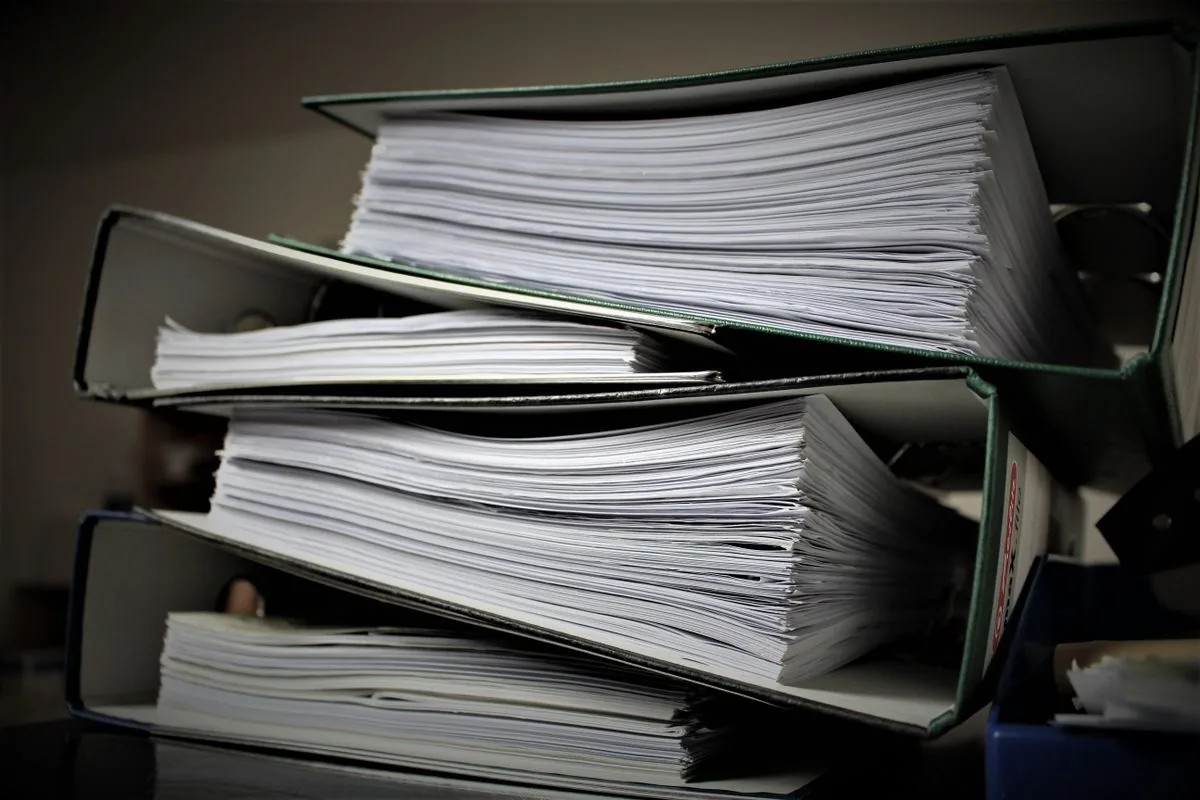 Carpetas apiladas con documentos de papel; foto de apoyo, no una captura de Gemini.